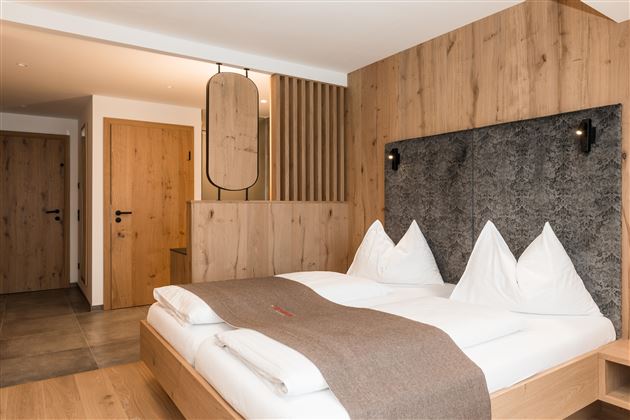 Ein modernes Schlafzimmer mit Holzverkleidung und einem komfortablen Doppelbett. Die Atmosphäre ist gemütlich und einladend.