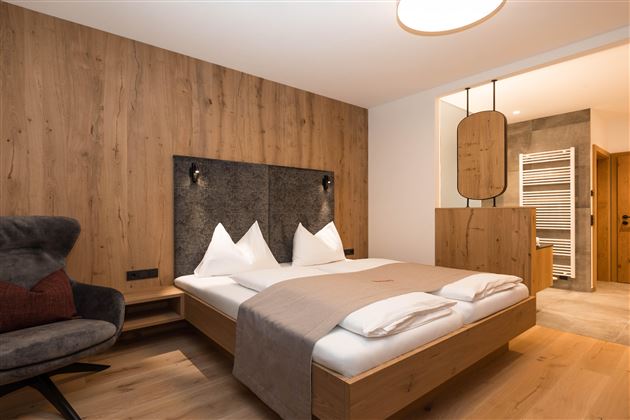 Ein modernes Schlafzimmer mit Holzwänden und einem gemütlichen Bett. Die Einrichtung ist stilvoll und gemütlich, ideal für Entspannung.