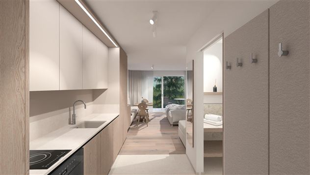 A modern kitchen with wooden cabinets and bright walls. In the background, a cozy living area with daylight can be seen.
