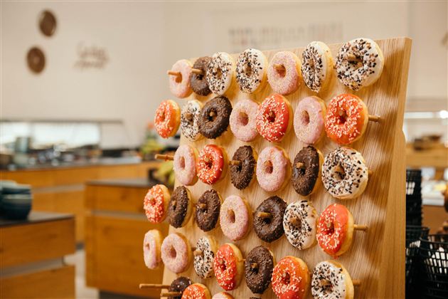 A wooden shelf with a colorful selection of donuts in various flavors and toppings. The donuts are neatly arranged and invite snacking.