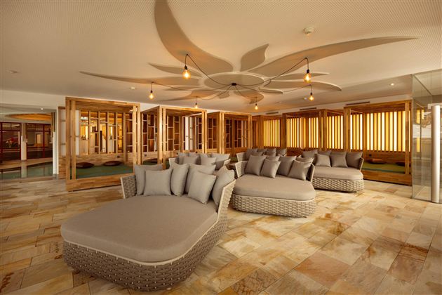 A stylish wellness area with comfortable lounge sofas and a warm ambiance. Large windows let gentle light in and create a relaxing atmosphere.
