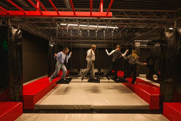 A trampoline hall with several bouncing elements. Four people are having fun playing and balancing.