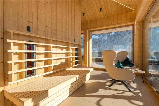 Ein modernes, helles Innenraum mit Holzverkleidung. Gemütliche Sitzgelegenheiten und große Fenster bieten einen Blick auf die Natur.