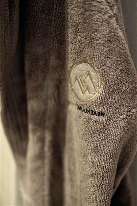 Ein graues Handtuch mit einem eingeprägten Logo. Es ist weich und scheint von hoher Qualität zu sein.