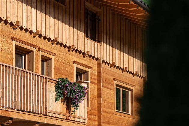 Ein Holzhaus mit einem Balkon, auf dem Blumen stehen. Die warmen Holzfarben verleihen dem Gebäude eine gemütliche Atmosphäre.
