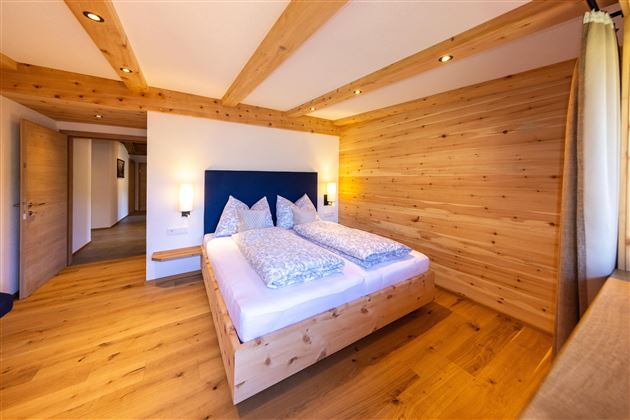 A modern bedroom with wooden paneling and a large double bed. The atmosphere is cozy and inviting.