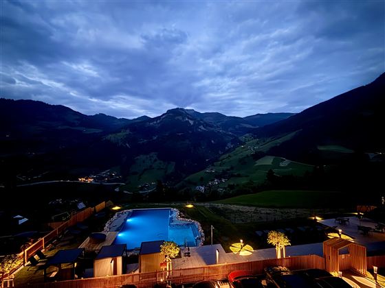 A beautiful view of the mountains at dusk. The illuminated pool in the center complements the idyllic scenery.
