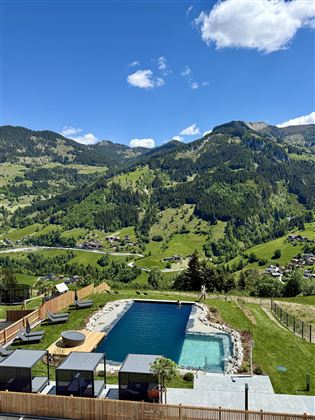 A beautiful pool amidst a green mountain landscape. The sunlight shines on the clouds and the surrounding hills.