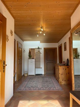 Ein heller Flur mit Holzdecke und Teppich. An den Wänden sind Türen und ein Spiegel zu sehen.