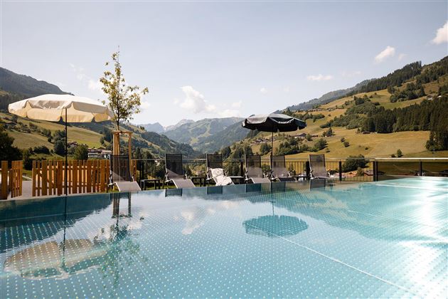 A beautiful infinity pool with a view of the mountains. Umbrellas and loungers invite you to relax.