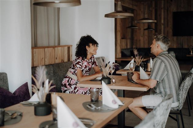 A cozy restaurant with wooden decor. Two people, a woman and a man, are sitting at the table and having a friendly conversation.