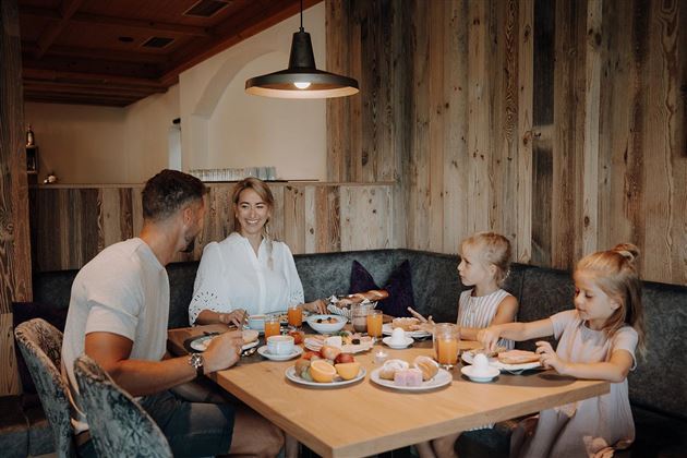 A cozy breakfast with a family at the table. The table is adorned with various foods and drinks.