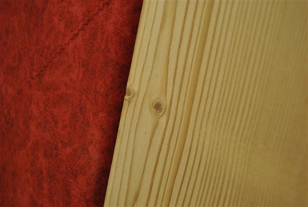 A piece of wood with visible growth rings and a smooth surface, combined with a red, textured material in the background. The colors and textures are clearly defined from each other.