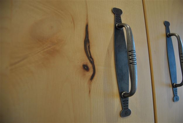 A wooden cabinet with elegant metal handles. A striking grain is visible on the surface.