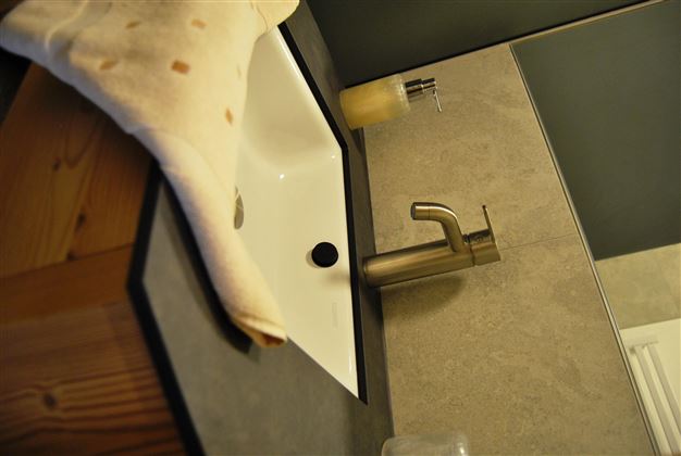 A modern bathroom with a white sink and an elegant faucet. The walls are in a neutral color tone, and a towel is loosely draped.