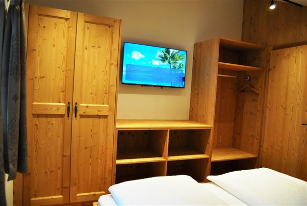 A cozy room with wooden furniture and a flat-screen TV. The space is bright and welcoming.