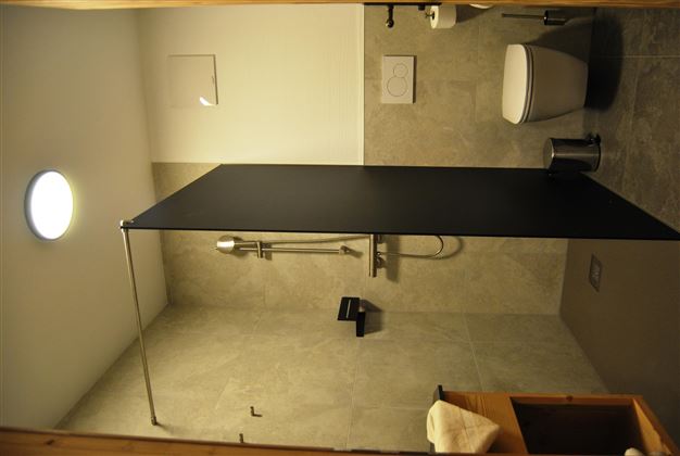 A modern bathroom with a shower and a toilet. The walls are painted in neutral shades of gray.
