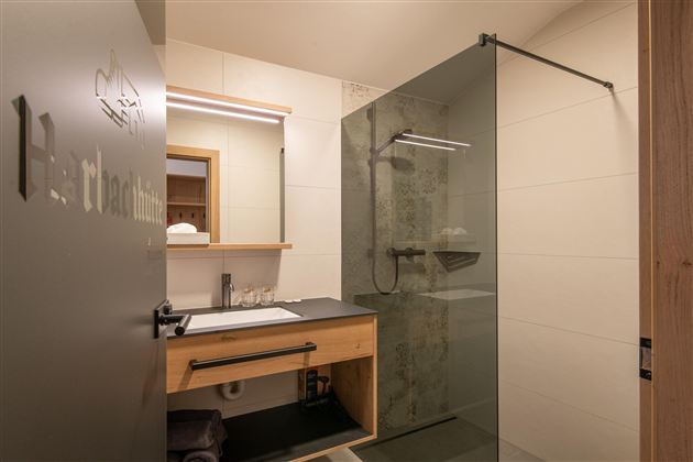 A modern bathroom with a glass shower and a wooden washbasin. The design is bright and inviting.