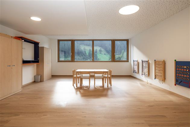 Ein heller Raum mit einem Tisch und Stühlen. Große Fenster bieten einen Blick auf die Landschaft.