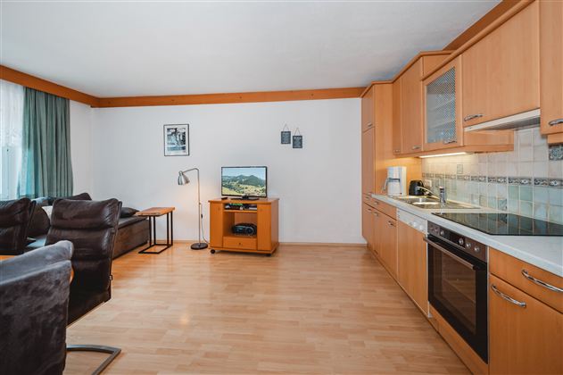 A bright and modernly furnished apartment with hardwood floors. The kitchen is well-equipped and there is a cozy seating area.