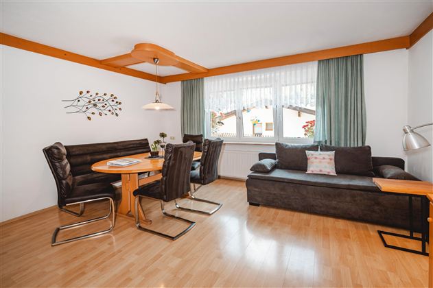A cozy living space with modern furniture. There is a dining table with chairs and a comfortable sofa.