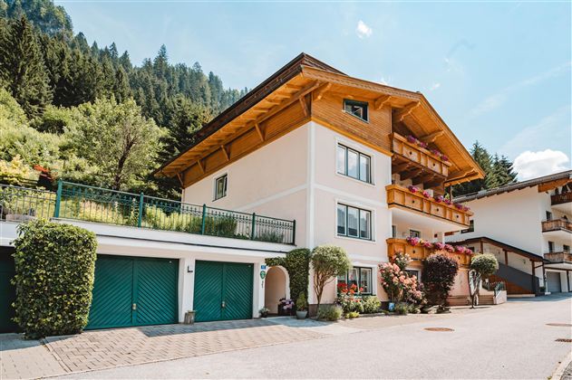 A charming house in alpine style with wooden balconies.  
Surrounded by green trees and a quiet street.