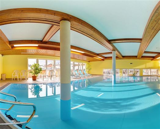 A bright indoor pool with blue water and plenty of natural light. Surrounded by comfortable loungers and a relaxed atmosphere.
