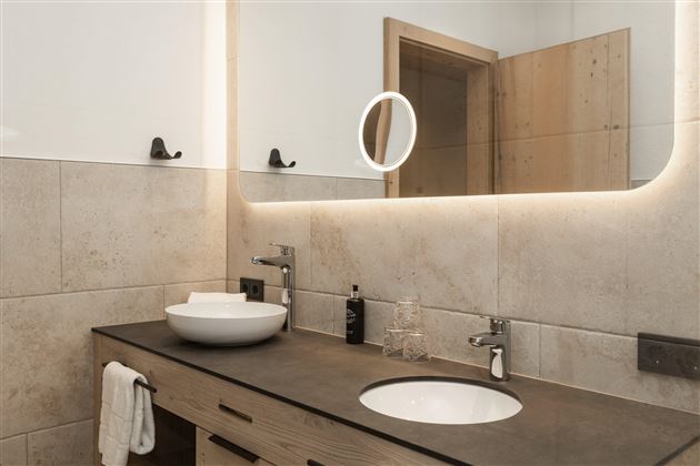 Ein modernes Badezimmer mit einem minimalistischen Design. Die hellen Fliesen und das schöne Waschbecken sorgen für eine einladende Atmosphäre.