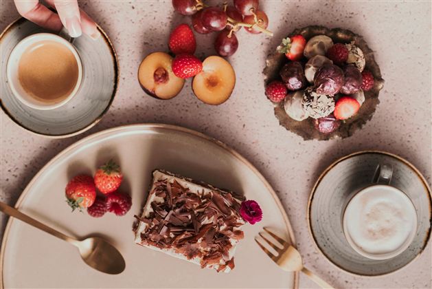 Eine leckere Auswahl an Desserts auf einem Tisch. Dazu gehören Kuchen, frisches Obst und Kaffee.