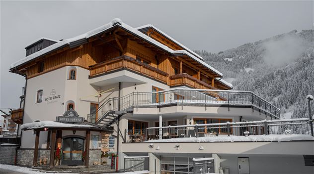 A charming hotel in the mountains, surrounded by snow-covered hills. The architecture combines traditional wooden design with modern elements.