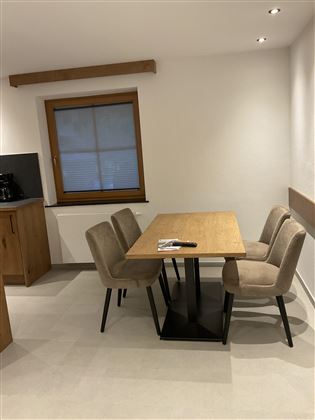 Ein moderner Essbereich mit einem Holztisch und vier beigen Stühlen. Das Zimmer hat große Fenster und eine helle, freundliche Atmosphäre.