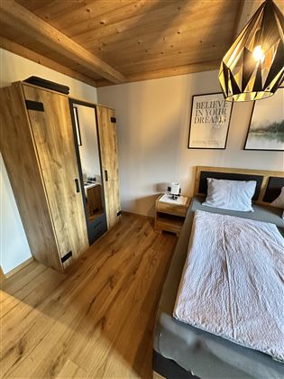 A modern bedroom with wooden furniture and a comfortable bed. The room is bright and inviting, with suitable lighting and decoration.