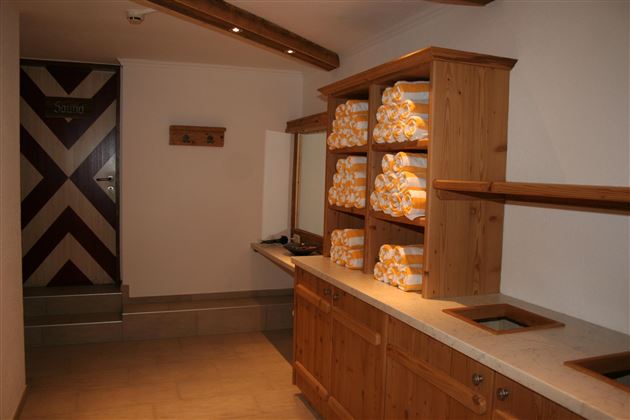 A modern bathroom with wooden shelves and stacks of towels. The walls are bright and the decor is simple and functional.