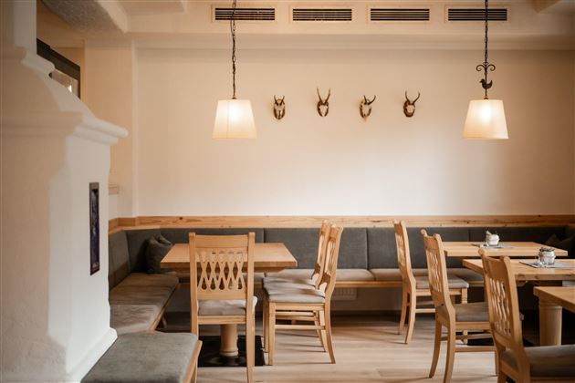 Ein gemütliches Restaurant mit Holztischen und Bänken. An der Wand hängen dekorative Geweihstücke.