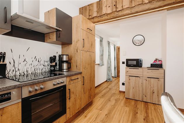 A modern kitchen with wooden cabinets and stainless steel appliances. It features a cozy dining area and a bright, inviting atmosphere.