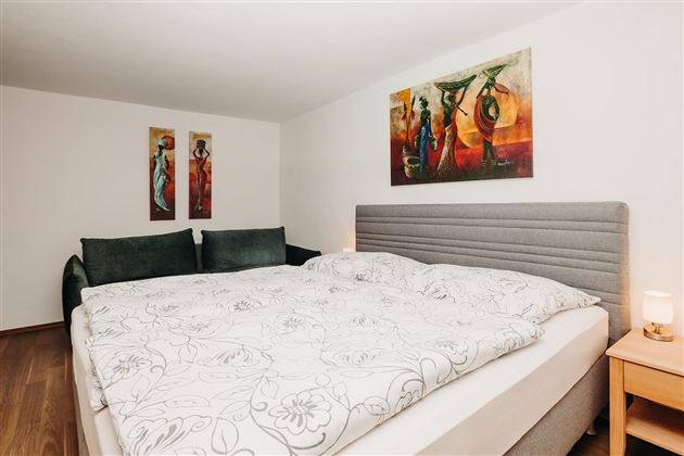 A cozy bedroom with a large double bed and colorful murals. The decor is modern and inviting.