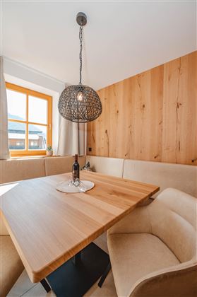 A cozy dining area with a wooden stove table and upholstered chairs. The ceiling lamp and the window create a pleasant atmosphere.
