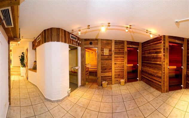 A modern wellness area with wooden paneling and sauna rooms. The space is brightly lit and invites relaxation.