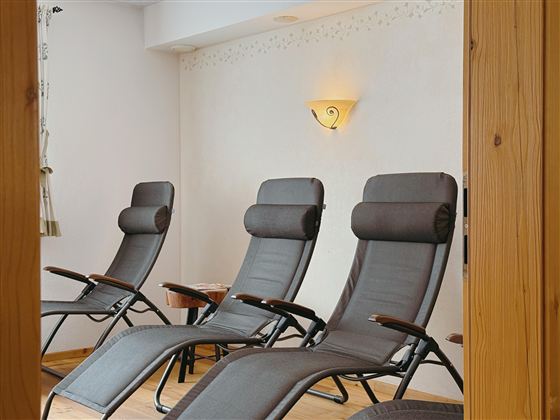 A relaxing room with several loungers. The walls are simple and bright, creating a calm atmosphere.