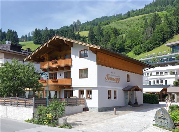 Ein charmantes alpine Haus mit Holzverkleidung und Balkonen. Umgeben von grünen Bergen und einer ruhigen Atmosphäre.