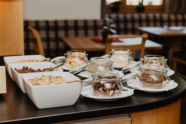 A lavish breakfast buffet with various cereals and dried fruits in jars. The presentation is appetizing and inviting.