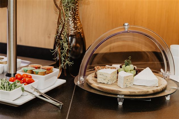 An attractively arranged buffet with a selection of cheese and fresh vegetables. The table is tastefully decorated and offers an appetizing presentation.