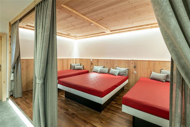 Ein modernes Schlafzimmer mit drei Einzelbetten und einem warmen Holzdesign. Die sanfte Beleuchtung schafft eine einladende Atmosphäre.