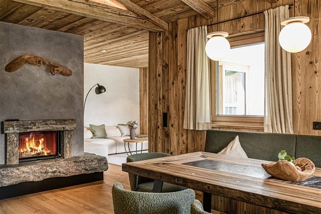 A cozy living space with wooden paneling and a modern fireplace. Large windows provide plenty of light and an inviting view outside.