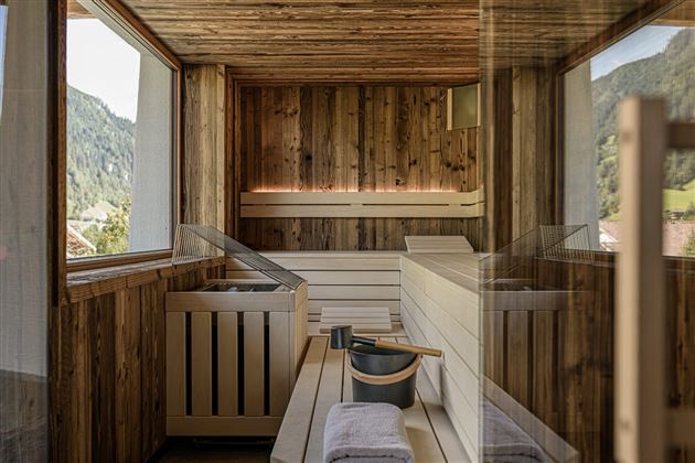 A modern wooden sauna with plenty of natural light. The beautiful mountain landscape can be seen through the windows.