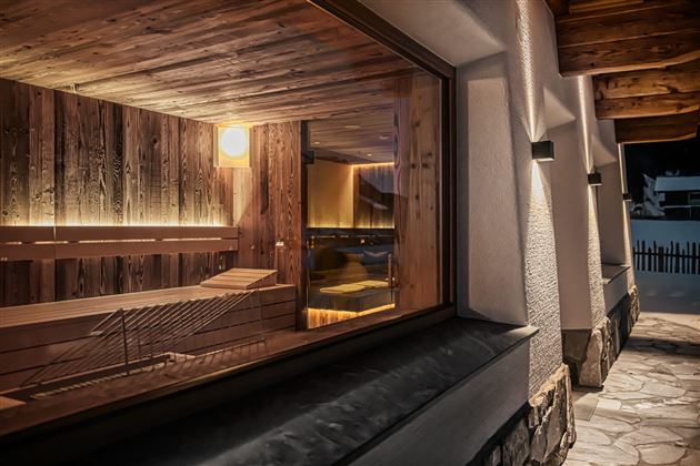 A stylish sauna with warm wooden interiors and soft lighting. The view showcases a cozy atmosphere outdoors.