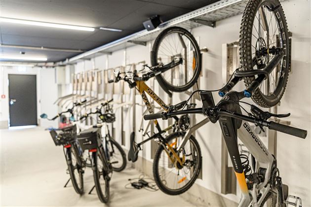 A bike room with several hanging bicycles on the wall. The environment is bright and designed in a modern style.