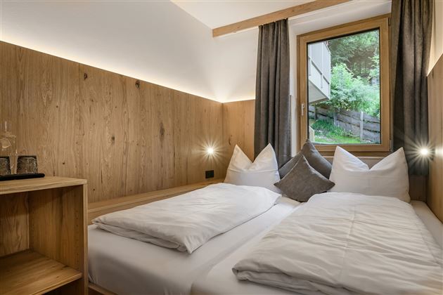 Ein gemütliches Schlafzimmer mit einem Doppelbett und einem großen Fenster. Die Wände sind aus Holz, und die Dekoration ist modern und einladend.