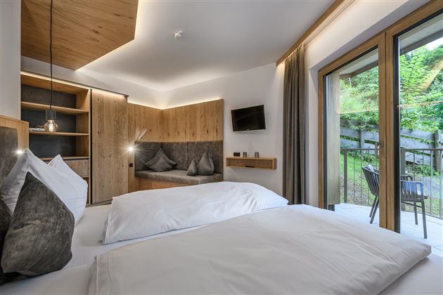 Ein modernes Zimmer mit zwei Betten und Holzverkleidung. Große Fenster bieten einen Blick ins Freie und sorgen für viel Tageslicht.