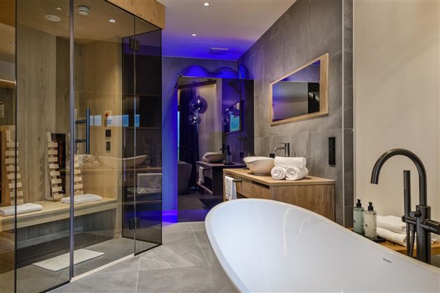 Ein modernes Badezimmer mit einer freistehenden Badewanne und großzügiger Dusche. Die Beleuchtung sorgt für eine entspannende Atmosphäre.